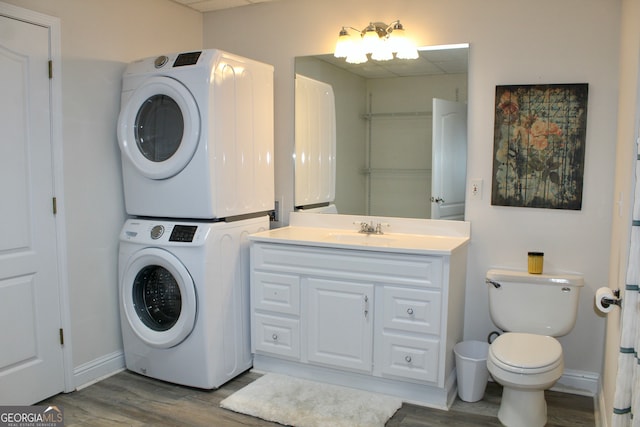 laundry room featuring sink, stacked washer and dryer, and hardwood / wood-style flooring