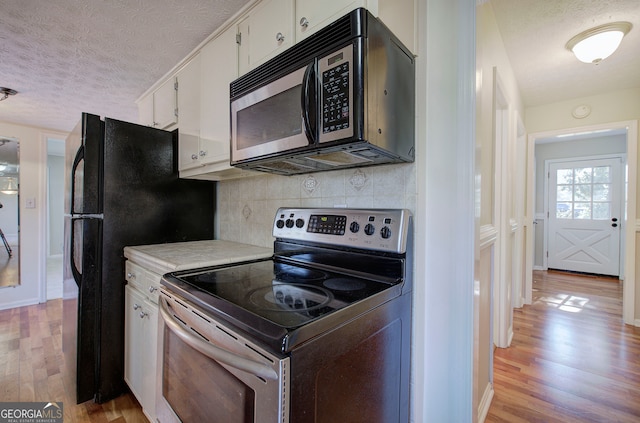 kitchen featuring white cabinets, light wood-type flooring, a textured ceiling, and appliances with stainless steel finishes