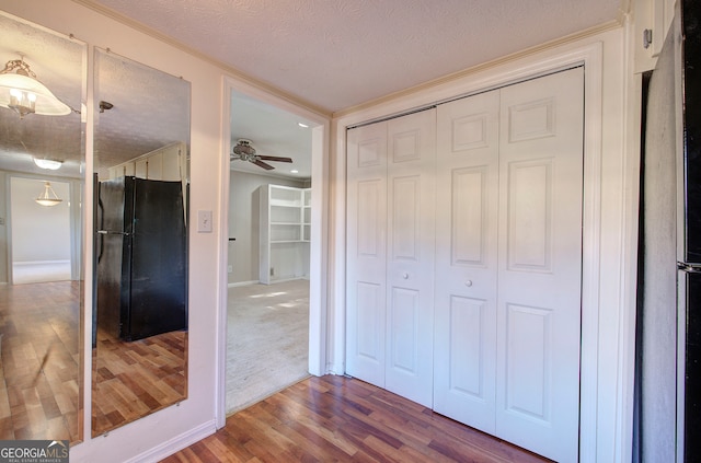 unfurnished bedroom with black refrigerator, refrigerator, a textured ceiling, wood-type flooring, and a closet