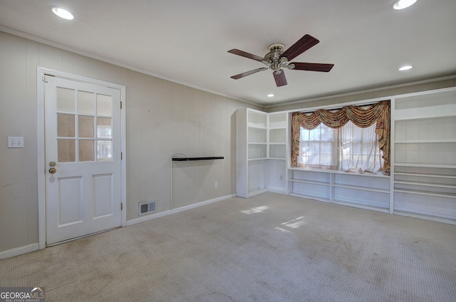 spare room with ceiling fan, light colored carpet, and crown molding