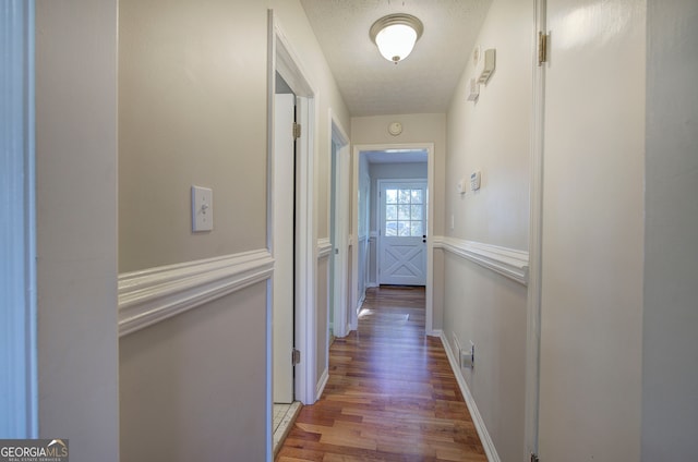 corridor featuring hardwood / wood-style floors and a textured ceiling