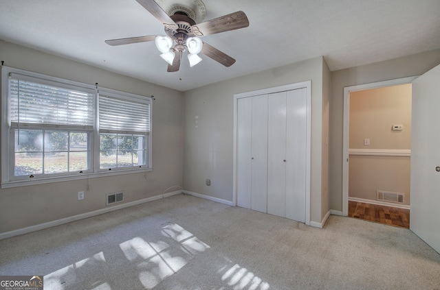 unfurnished bedroom featuring ceiling fan, a closet, and light carpet