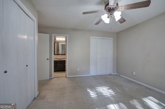 unfurnished bedroom with light colored carpet, ensuite bath, and ceiling fan