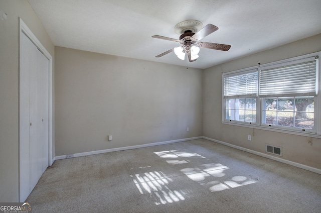 unfurnished bedroom with ceiling fan, light colored carpet, and a closet