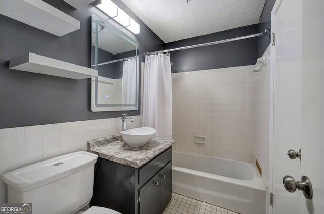 full bathroom with shower / bath combo, tile patterned flooring, toilet, vanity, and tile walls