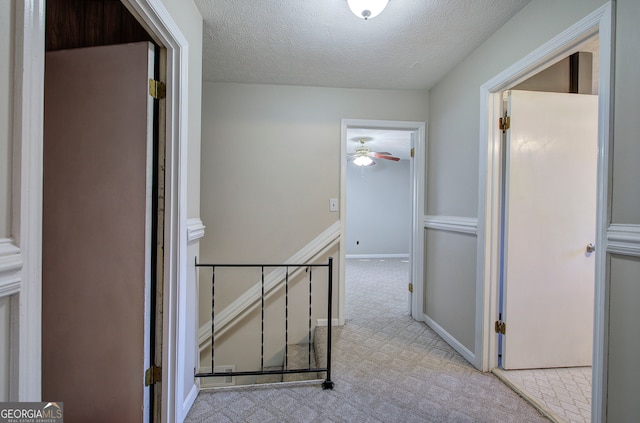 hall featuring light colored carpet and a textured ceiling