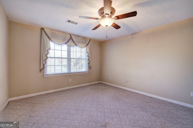 spare room with a textured ceiling, light colored carpet, and ceiling fan