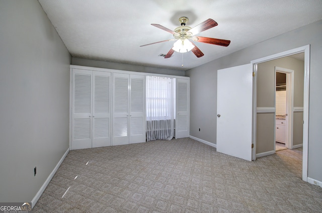 unfurnished bedroom with ceiling fan, light carpet, and a closet