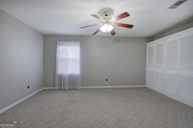 unfurnished bedroom with ceiling fan, light colored carpet, and a textured ceiling