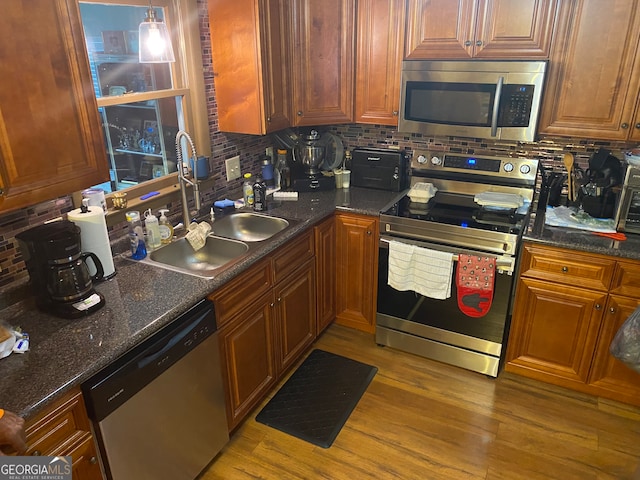 kitchen featuring decorative backsplash, appliances with stainless steel finishes, sink, hardwood / wood-style flooring, and decorative light fixtures