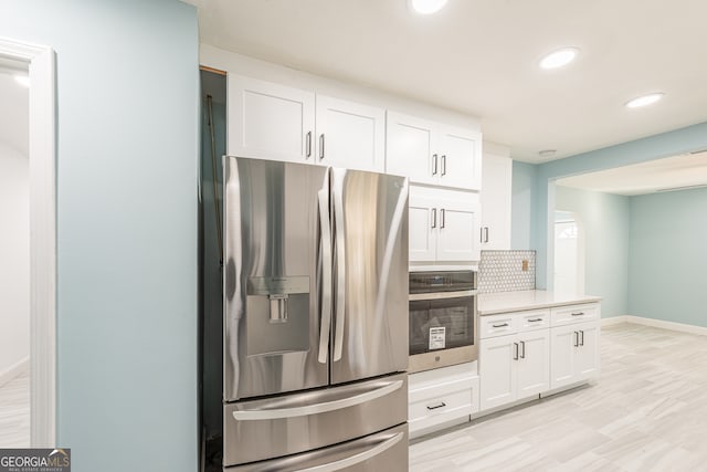 kitchen featuring white cabinets, appliances with stainless steel finishes, and backsplash