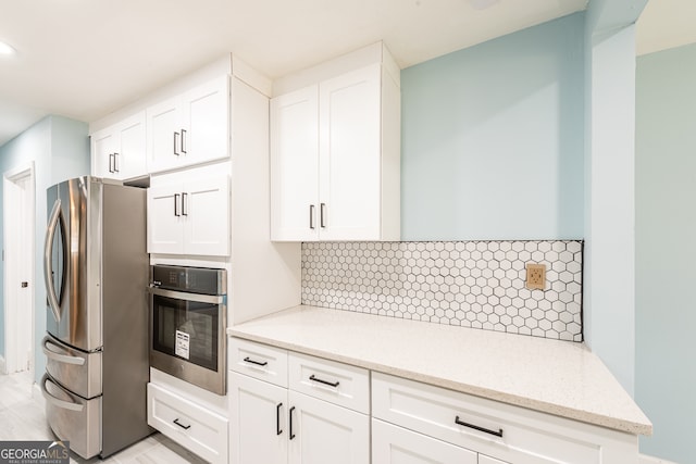 kitchen with decorative backsplash, stainless steel appliances, and white cabinetry