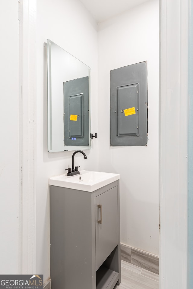 bathroom with electric panel, hardwood / wood-style floors, and vanity