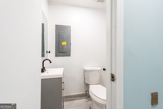 bathroom with electric panel, vanity, and toilet