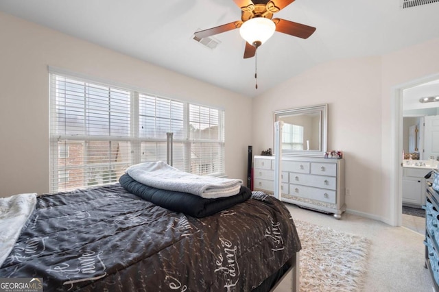 carpeted bedroom featuring ceiling fan, vaulted ceiling, connected bathroom, and multiple windows