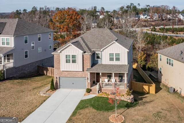 view of front of home featuring a porch, central AC unit, a garage, and a front lawn