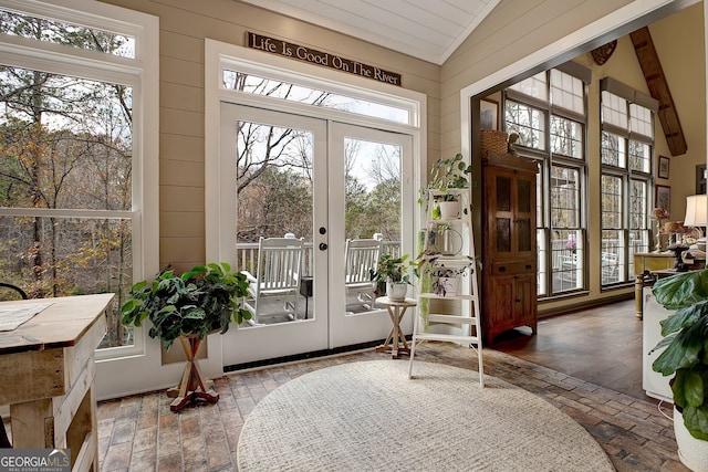 interior space with plenty of natural light, wood-type flooring, french doors, and vaulted ceiling