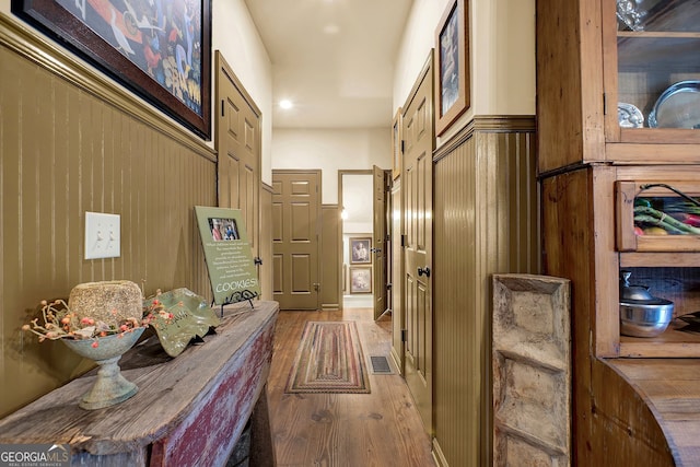 corridor featuring wooden walls and light wood-type flooring