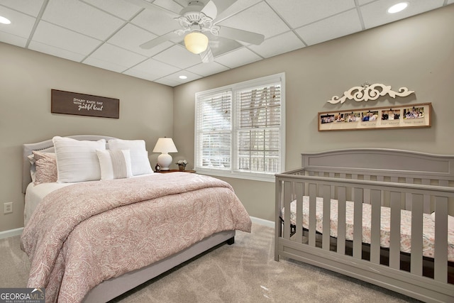 carpeted bedroom featuring ceiling fan and a drop ceiling