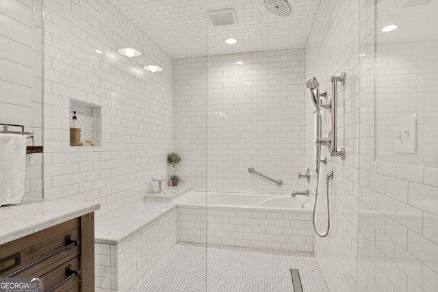 bathroom with vanity, tile patterned floors, tile walls, and tiled shower / bath combo