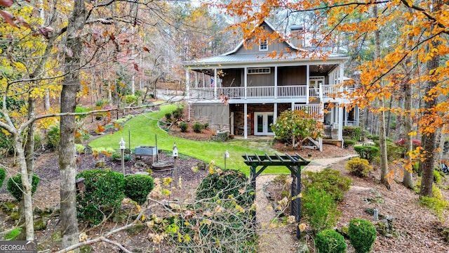 rear view of property featuring a yard, a sunroom, and french doors