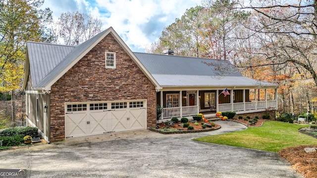 view of front of home with covered porch, a garage, and a front lawn