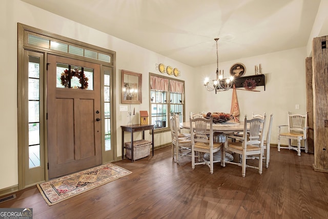 dining space with dark wood-type flooring and a chandelier