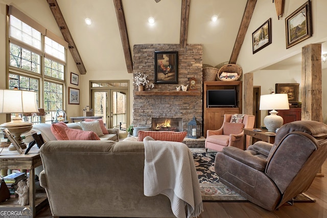 living room featuring hardwood / wood-style flooring, beam ceiling, a stone fireplace, and high vaulted ceiling