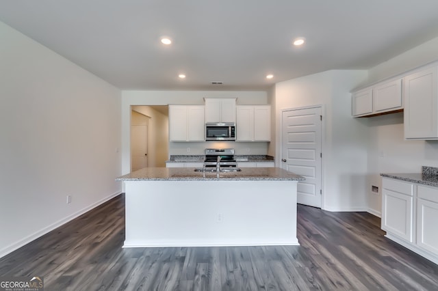 kitchen with dark hardwood / wood-style floors, white cabinetry, and a kitchen island with sink