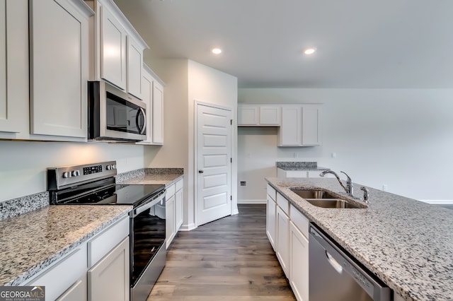 kitchen with light stone counters, stainless steel appliances, sink, wood-type flooring, and white cabinets