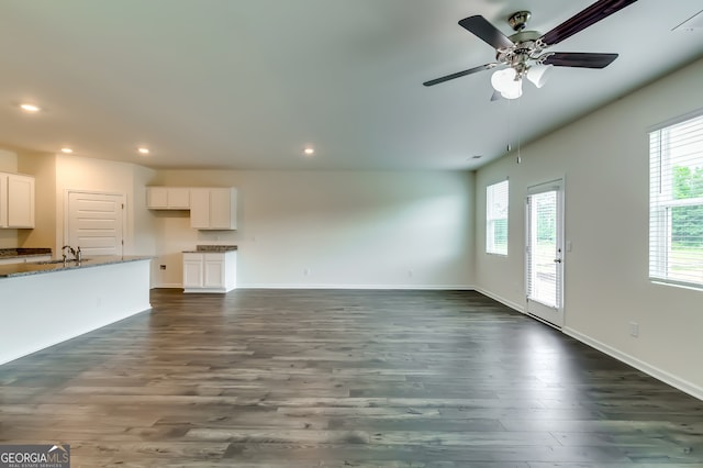 unfurnished living room featuring ceiling fan, sink, and dark wood-type flooring