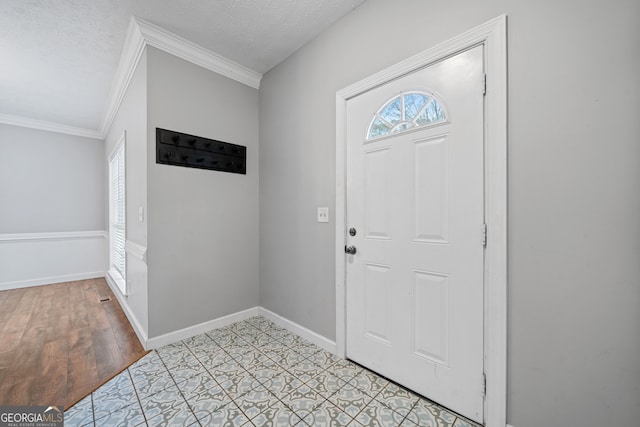 entrance foyer with a textured ceiling, light hardwood / wood-style floors, and crown molding