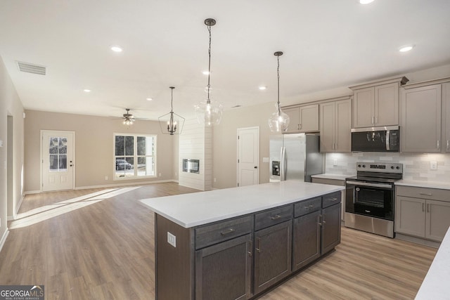 kitchen featuring ceiling fan, hanging light fixtures, light wood-type flooring, and appliances with stainless steel finishes