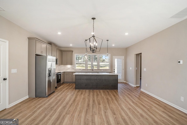 kitchen featuring gray cabinetry, a center island, a chandelier, decorative light fixtures, and appliances with stainless steel finishes