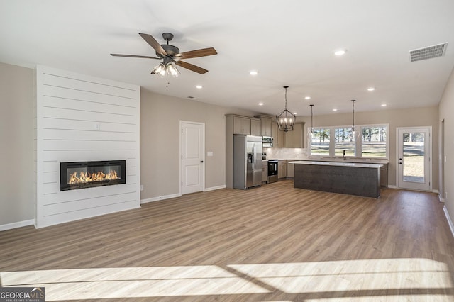 kitchen with a center island, hanging light fixtures, light hardwood / wood-style flooring, a fireplace, and appliances with stainless steel finishes