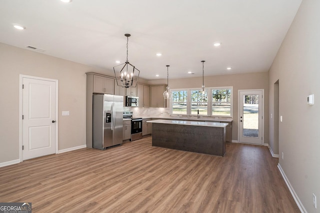 kitchen with backsplash, gray cabinetry, stainless steel appliances, pendant lighting, and a center island