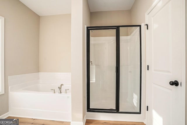 bathroom with hardwood / wood-style floors and independent shower and bath