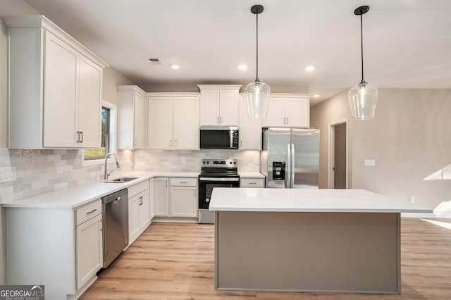 kitchen featuring white cabinetry, a kitchen island, decorative light fixtures, and appliances with stainless steel finishes