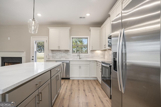 kitchen featuring white cabinets, sink, decorative backsplash, appliances with stainless steel finishes, and decorative light fixtures