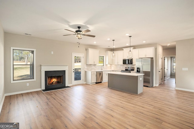 kitchen featuring ceiling fan, hanging light fixtures, a kitchen island, white cabinets, and appliances with stainless steel finishes