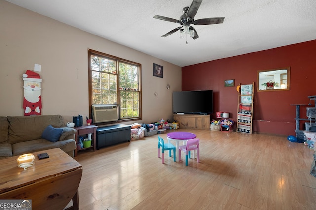 game room with a textured ceiling, light wood-type flooring, and ceiling fan