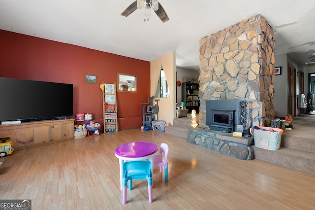 living room featuring a wood stove, ceiling fan, and hardwood / wood-style floors