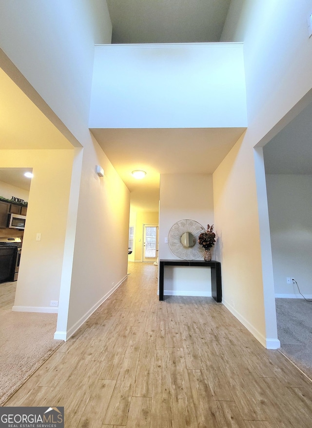 hallway with a high ceiling and light hardwood / wood-style floors