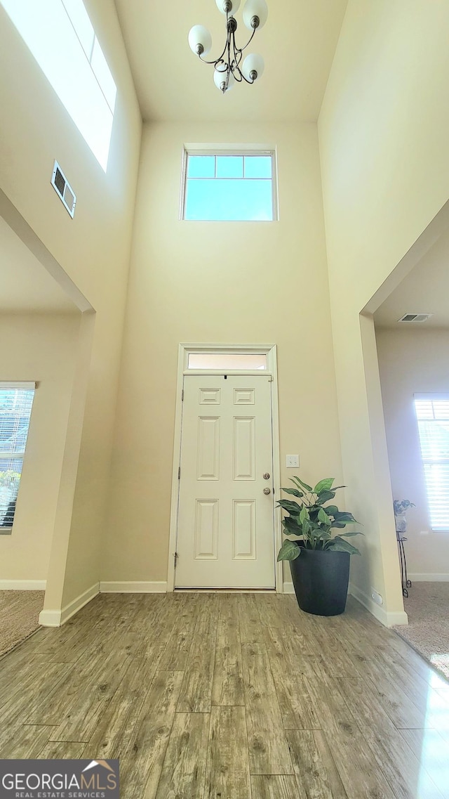 entryway with hardwood / wood-style flooring, a high ceiling, and an inviting chandelier