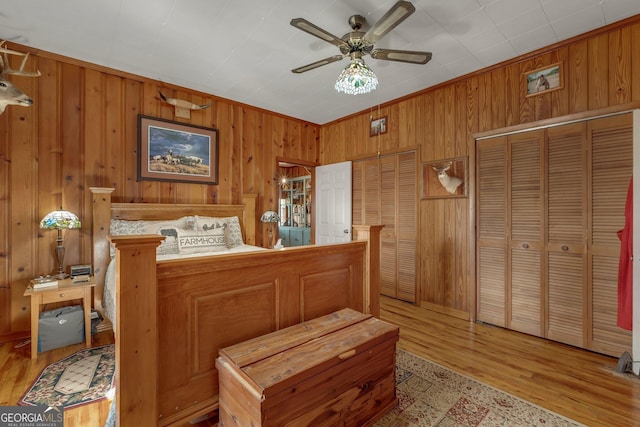 bedroom featuring light hardwood / wood-style flooring, ceiling fan, crown molding, and wood walls