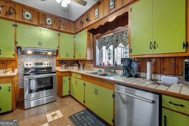 kitchen with appliances with stainless steel finishes, tasteful backsplash, ceiling fan, sink, and tile countertops