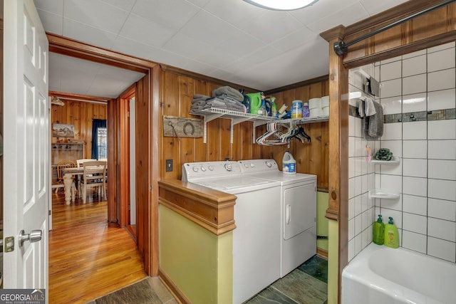 laundry room with hardwood / wood-style flooring, separate washer and dryer, and wooden walls