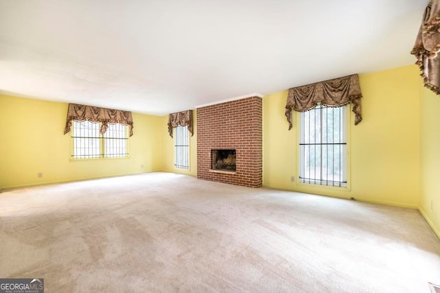 unfurnished living room with a wealth of natural light, a fireplace, and light colored carpet