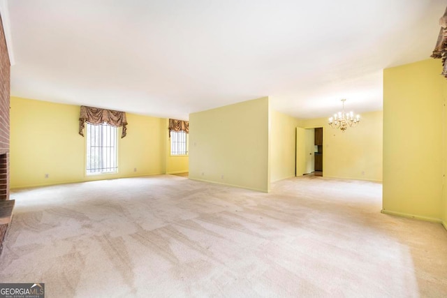 carpeted empty room featuring a notable chandelier and a brick fireplace