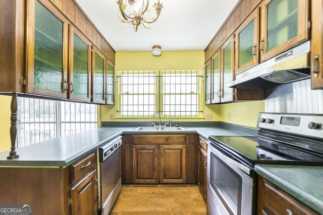 6909 Forsyth Rd, Macon, GA 31210 - kitchen with appliances with stainless steel finishes, under cabinet range hood, a chandelier, glass insert cabinets, and a peninsula